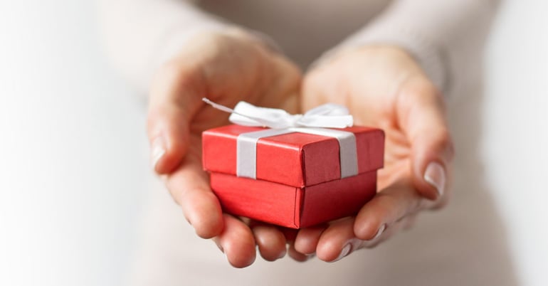 hands holding red gift box holiday giving